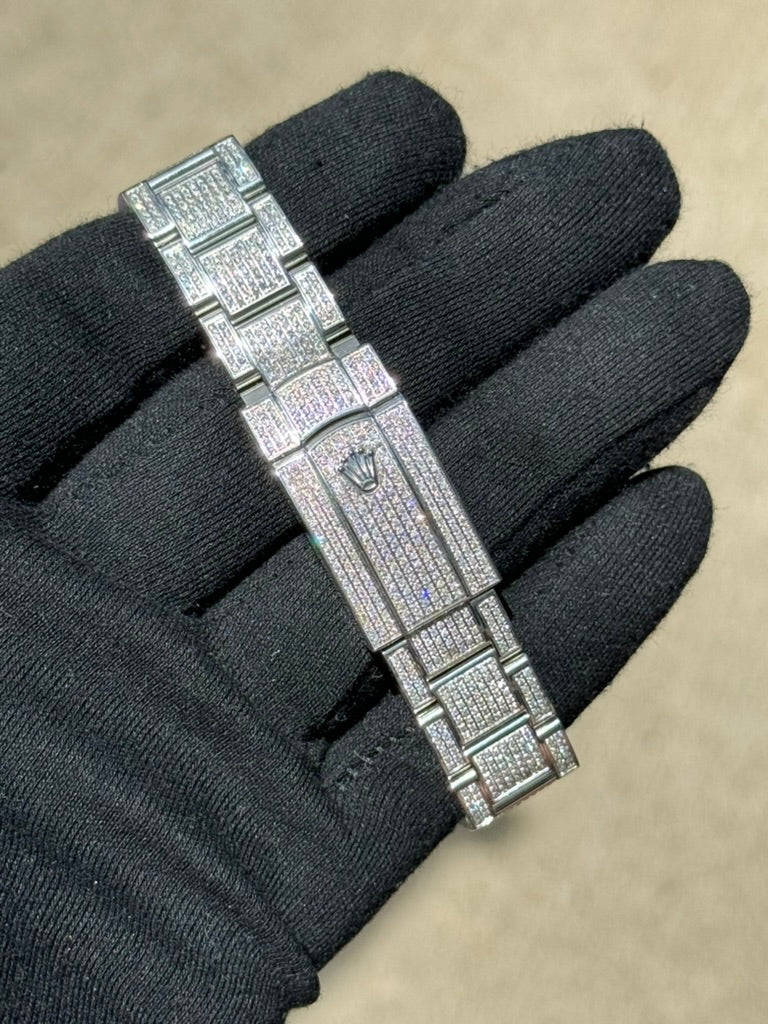 A gloved hand is holding a silver bracelet encrusted with diamonds and featuring a crown logo, reminiscent of the elegance seen in a Rolex Datejust 126300 "Bust Down" by Rolex.